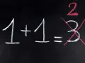 Na czarnej tablicy napisano kredą: 1+1=3. Dwójka jest podkreślona na czerwono, a trójka przekreślona. Jak na egzaminie dojrzałości, gdzie liczy się poprawna odpowiedź.