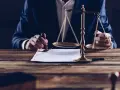 Sądowa waga sprawiedliwości i ręka stemplująca dokument.