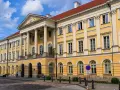 Imponujący żółty budynek z kolumnami, symbol jednych z najlepszych uczelni w Polsce.