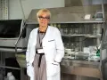Patomorfolog w białym fartuchu stoi w laboratorium, otoczona sprzętem i odczynnikami.