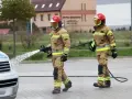 Dwóch strażaków PSP w akcji, jeden z wężem wodnym. Ciekawe, ile zarabia strażak w PSP za taką pracę.