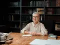 Uśmiechnięta pani z okularami, gotowa do matury ustnej z polskiego. W tle regały pełne książek.