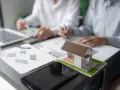 Model domu na biurku, gdzie trwa dyskusja o gospodarce przestrzennej.
