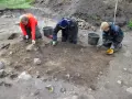 Antropologowie pracują na stanowisku archeologicznym, ostrożnie badając ziemię.