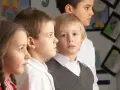 Dzieci w szkole, skupione na lekcji. Widać ich twarze i fragmenty ubrań. To może być przykład nauczania indywidualnego.
