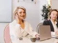 Dwie kobiety w biurze, jedna rozmawia przez telefon, druga pisze.
