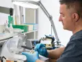 Technik dentystyczny w rękawiczkach pracuje nad modelem zębów przy użyciu pędzelka.