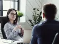 Kobieta w okularach prowadzi rozmowę kwalifikacyjną z mężczyzną.
