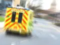 Ambulans w ruchu na drodze, z widocznym napisem AMBULANCE.