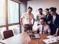 Zespół świętuje sukces. Mężczyzna, który jest business development managerem, wskazuje na ekran laptopa.