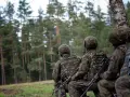 Żołnierze w mundurach polowych, przygotowujący się do ćwiczeń w lesie. To obraz dobrowolnej zasadniczej służby wojskowej.