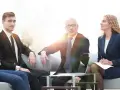 Biznesmeni dyskutują podczas spotkania. Młody mężczyzna w garniturze, starszy mężczyzna w okularach i kobieta w granatowym kostiumie tworzą zespół, który może być częścią rady nadzorczej.
