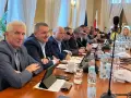Mężczyźni przy stole obradują, dyskutując o przyznaniu absolutorium.