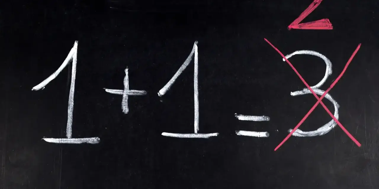 Na czarnej tablicy napisano kredą: 1+1=3. Dwójka jest podkreślona na czerwono, a trójka przekreślona. Jak na egzaminie dojrzałości, gdzie liczy się poprawna odpowiedź.