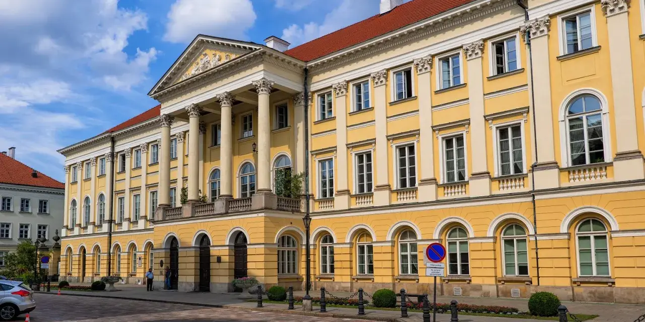 Imponujący żółty budynek z kolumnami, symbol jednych z najlepszych uczelni w Polsce.