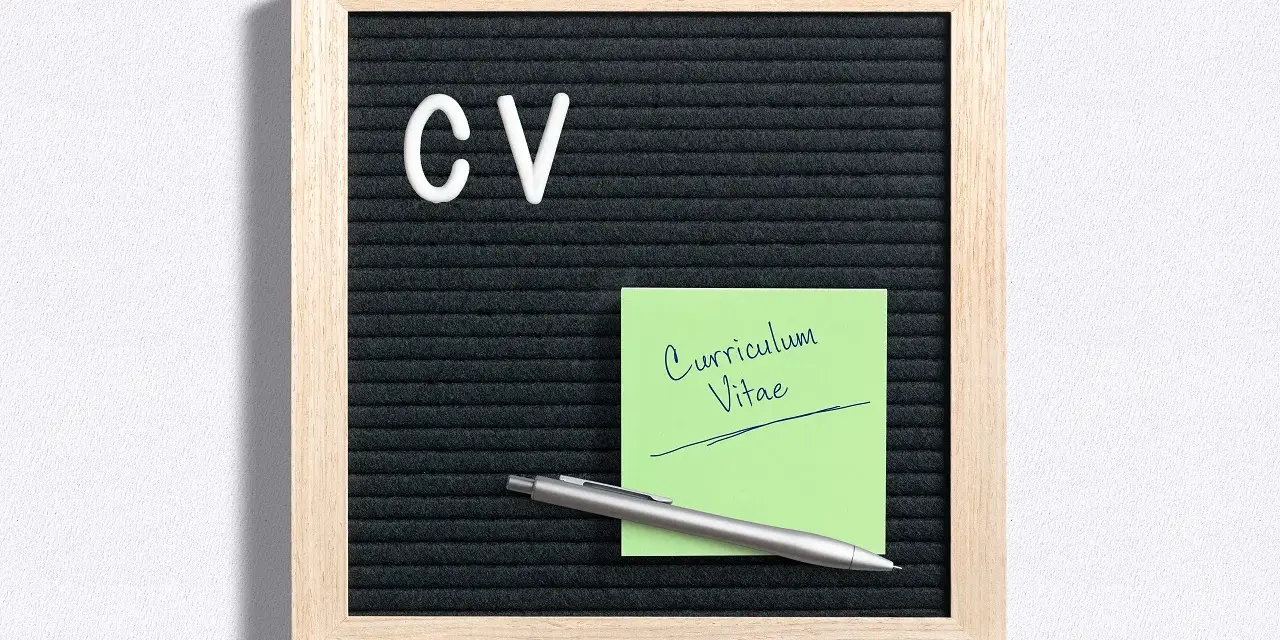 Tablica z literami "CV" i zielona karteczka z napisem "Curriculum Vitae". Idealne do przygotowania CV po niemiecku.
