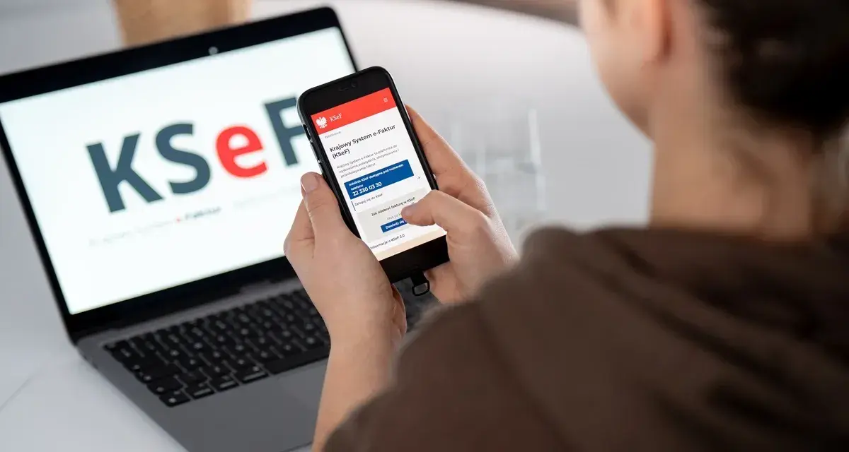 Osoba korzysta z telefonu, by dowiedzieć się, jak wystawić fakturę w KSeF. Na ekranie telefonu widoczna jest instrukcja.