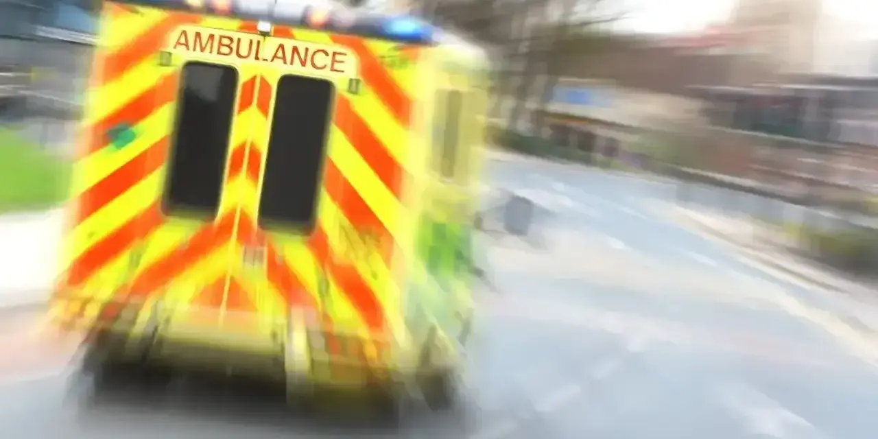 Ambulans w ruchu na drodze, z widocznym napisem AMBULANCE.
