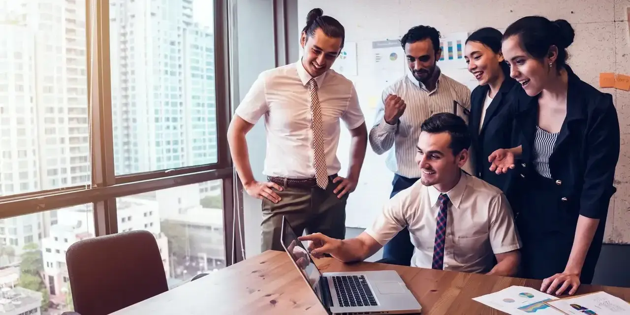Zespół świętuje sukces. Mężczyzna, który jest business development managerem, wskazuje na ekran laptopa.