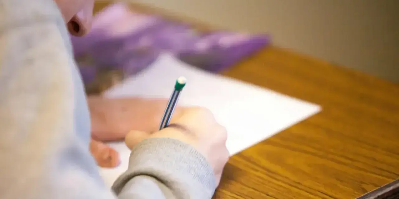 Uczeń pisze wypracowanie, starając się zdobyć jak najwięcej punktów na maturze z polskiego.