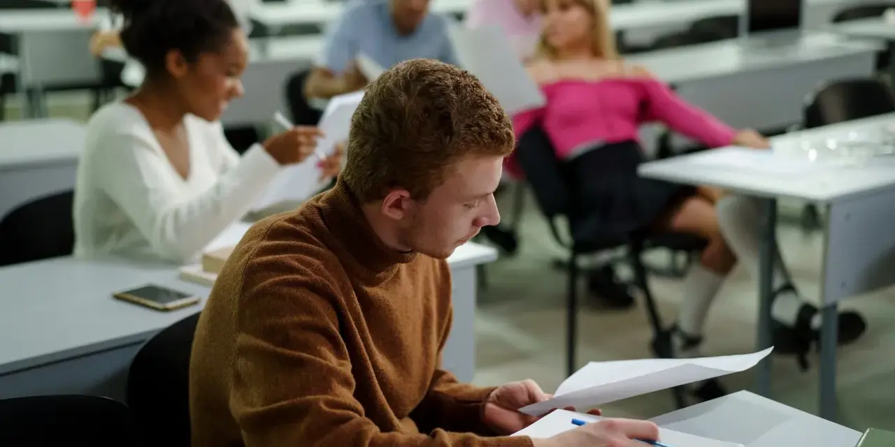 Studenci w sali wykładowej, skupieni na nauce. To dowód, że studia bez matury są możliwe i otwierają drzwi do wiedzy.