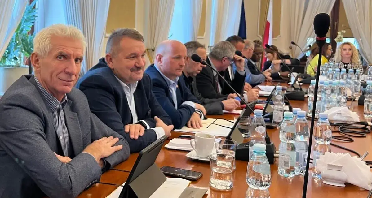 Mężczyźni przy stole obradują, dyskutując o przyznaniu absolutorium.