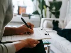 Psycholog notuje podczas sesji. Zastanawia się nad zarobkami i rozwojem kariery.