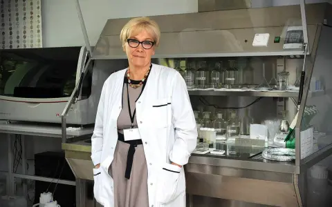 Patomorfolog w białym fartuchu stoi w laboratorium, otoczona sprzętem i odczynnikami.