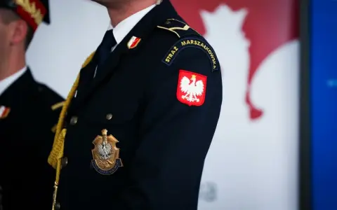Urzędnik w granatowym mundurze z godłem Polski i napisem "STRAŻ MARSZAŁKOWSKA" na rękawie.