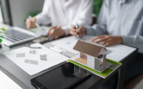 Model domu na biurku, gdzie trwa dyskusja o gospodarce przestrzennej.
