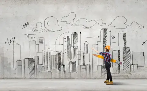Studentka architektury z wielkim ołówkiem rysuje miasto na ścianie.