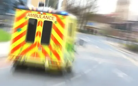 Ambulans w ruchu na drodze, z widocznym napisem AMBULANCE.