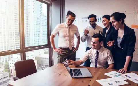 Zespół świętuje sukces. Mężczyzna, który jest business development managerem, wskazuje na ekran laptopa.