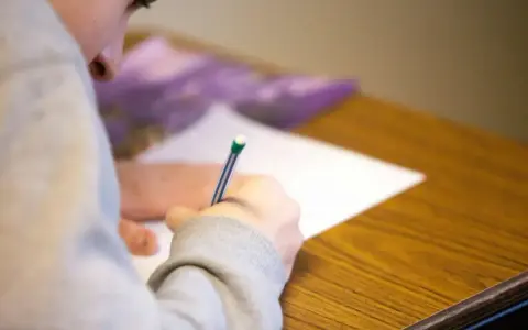 Uczeń pisze wypracowanie, starając się zdobyć jak najwięcej punktów na maturze z polskiego.