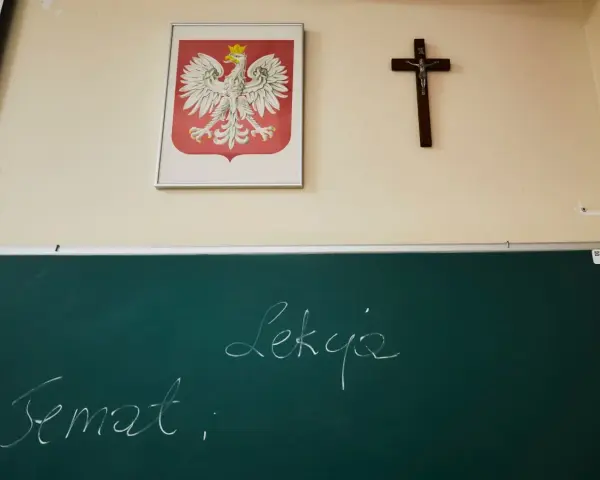 Na ścianie wisi godło Polski i krzyż. Na tablicy napisano "Temat: Lekcja". Czy religia wlicza się do średniej?