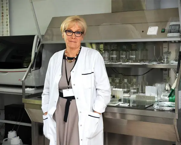Patomorfolog w białym fartuchu stoi w laboratorium, otoczona sprzętem i odczynnikami.