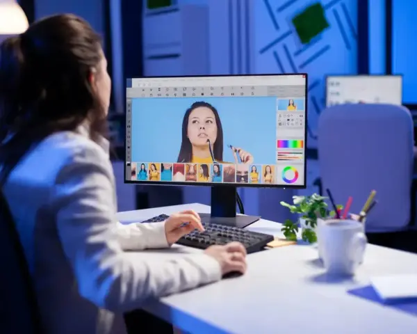 Kobieta edytuje zdjęcia na komputerze, zastanawiając się, ile zarabia grafik komputerowy.