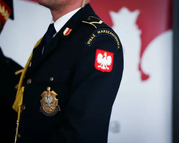 Urzędnik w granatowym mundurze z godłem Polski i napisem "STRAŻ MARSZAŁKOWSKA" na rękawie.