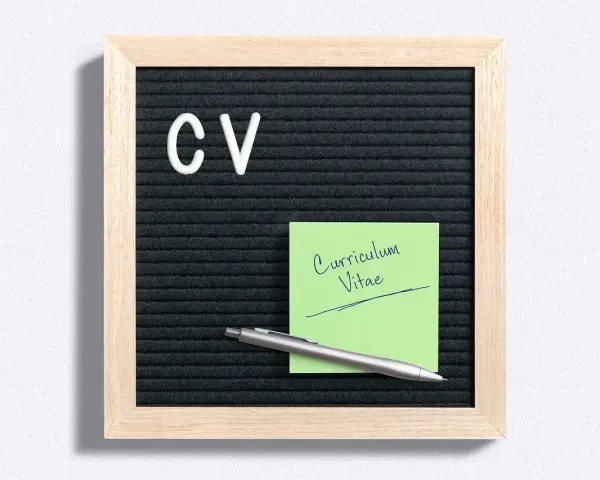 Tablica z literami "CV" i zielona karteczka z napisem "Curriculum Vitae". Idealne do przygotowania CV po niemiecku.