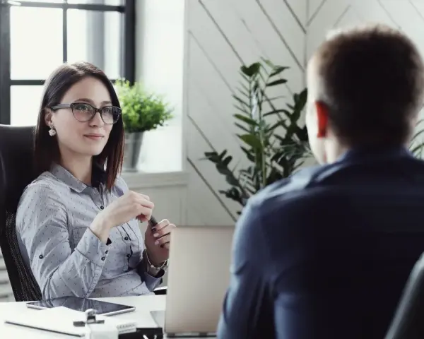 Kobieta w okularach prowadzi rozmowę kwalifikacyjną z mężczyzną.
