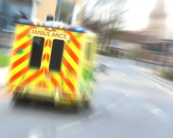 Ambulans w ruchu na drodze, z widocznym napisem AMBULANCE.
