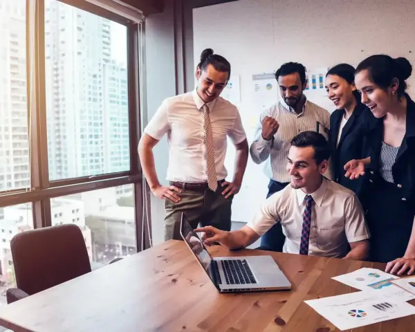 Zespół świętuje sukces. Mężczyzna, który jest business development managerem, wskazuje na ekran laptopa.