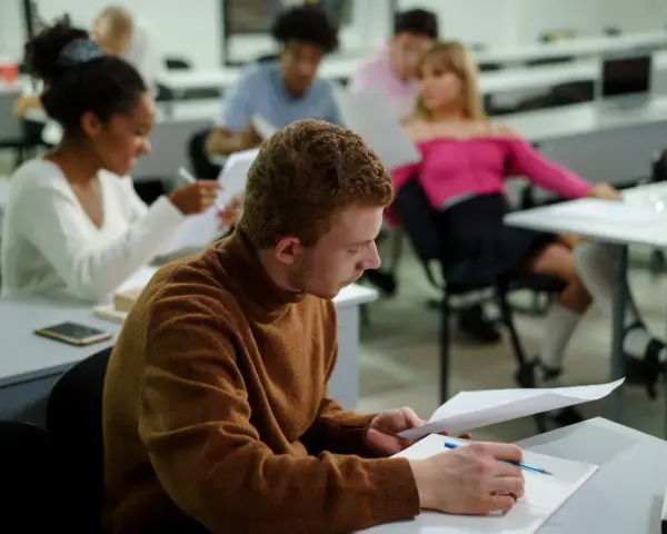 Studenci w sali wykładowej, skupieni na nauce. To dowód, że studia bez matury są możliwe i otwierają drzwi do wiedzy.