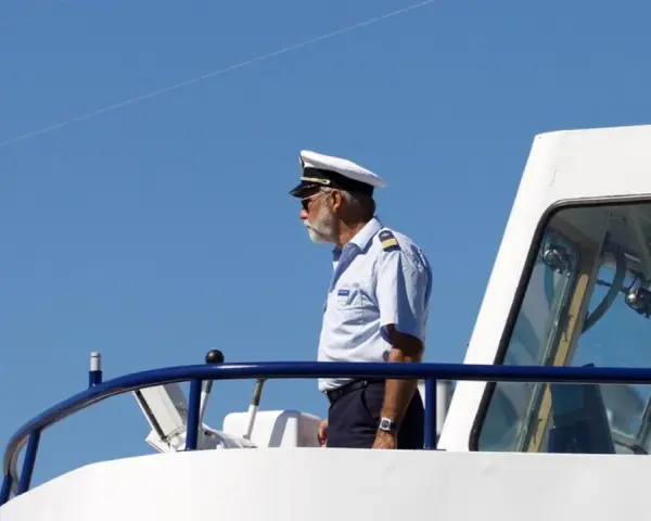 Kapitan na mostku statku, zastanawia się, ile zarabia marynarz.