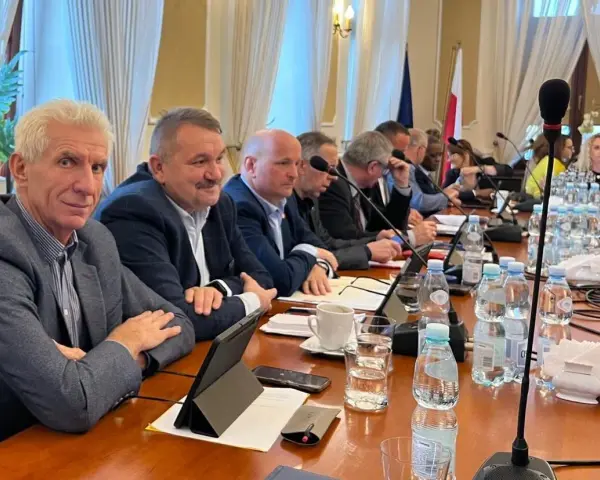 Mężczyźni przy stole obradują, dyskutując o przyznaniu absolutorium.