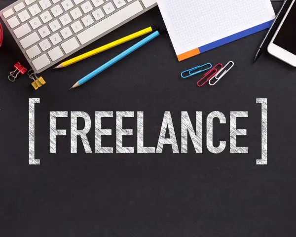 Klawiatura, telefony, ołówki i spinacze na czarnym tle. Napis "FREELANCE" sugeruje, jak zacząć pracę jako wolny strzelec.