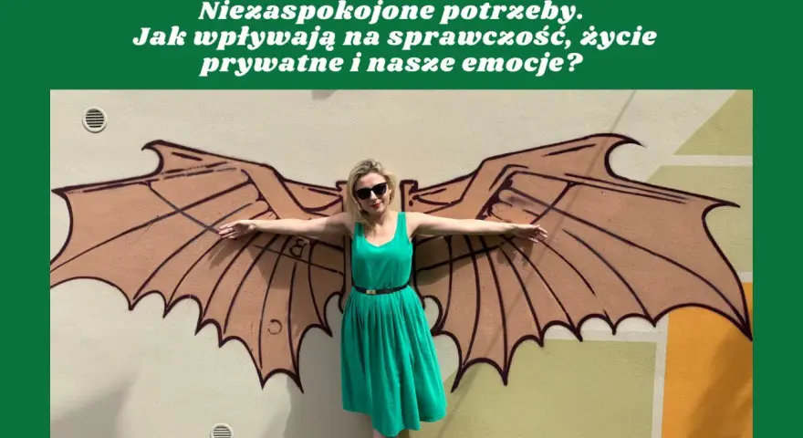 Kobieta w zielonej sukience stoi przed muralem z brązowymi skrzydłami.