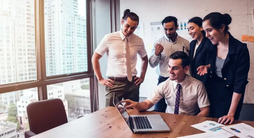 Zespół świętuje sukces. Mężczyzna, który jest business development managerem, wskazuje na ekran laptopa.
