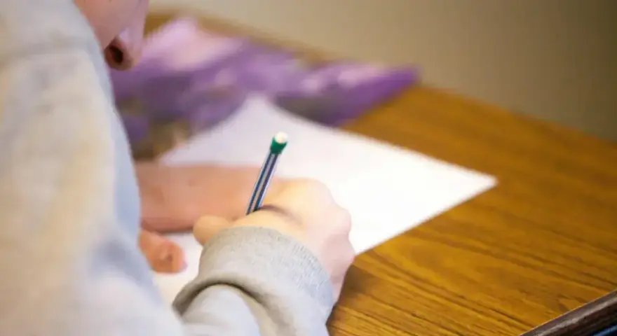 Uczeń pisze wypracowanie, starając się zdobyć jak najwięcej punktów na maturze z polskiego.